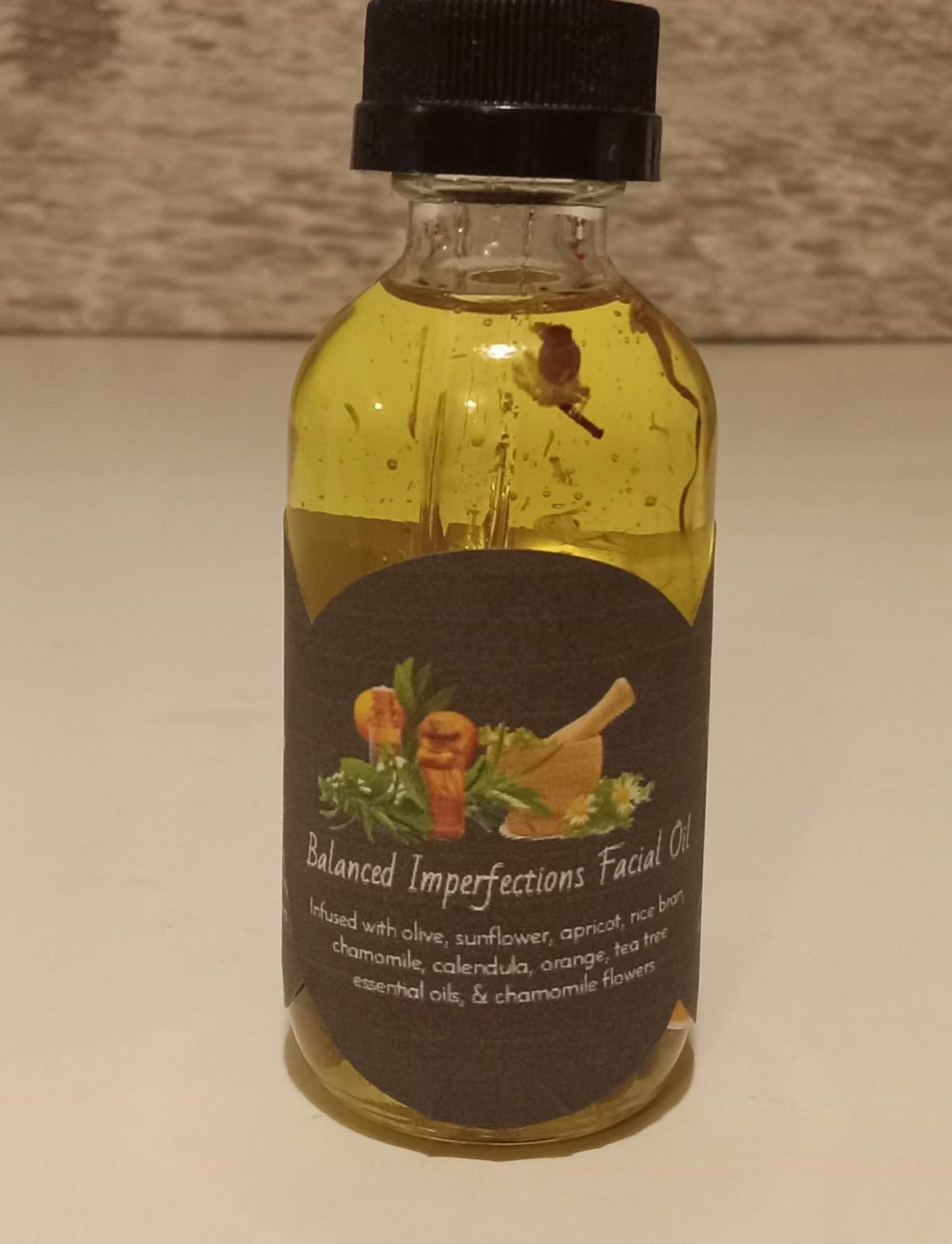 Chamomile Sunshine Face Oil in a glass bottle with chamomile flowers, aloe vera, and tea tree leaves on a wooden surface.